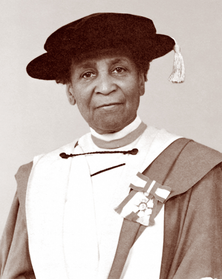a woman looks at the camera wearing academic robe and hat