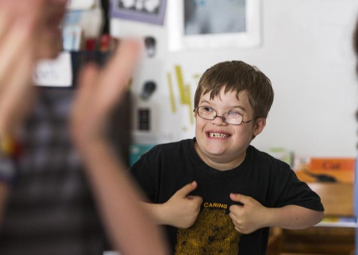 image of a young boy in what appears to be a daycare setting with a blurred image of an adult woman in the background