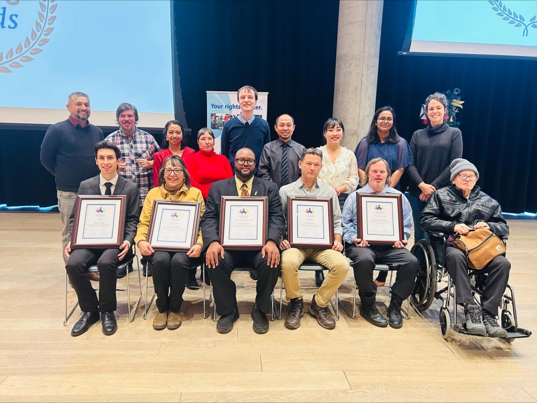 a smiling group of people holding framed award ceritficates
