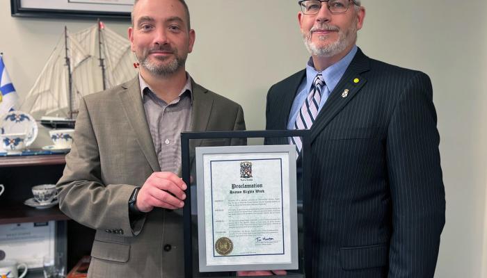Commission CEO Joe Fraser and Justice Minister Brad Johns pose with a framed proclamaiton certifiacte